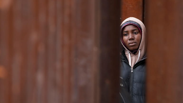 A migrant woman waits between two border walls hoping to...