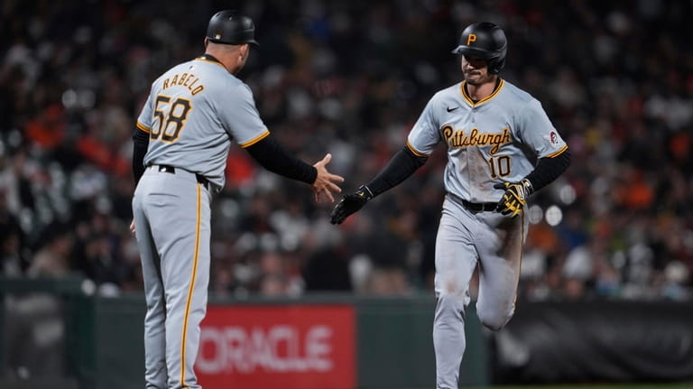 Pittsburgh Pirates' Bryan Reynolds, right, celebrates with third base coach...