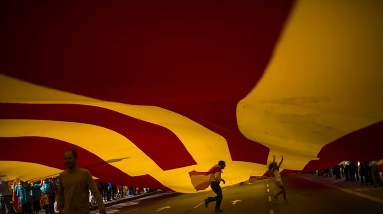 People walk under a huge Spanish flag as they celebrate...