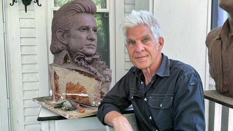 Artist Kevin Kresse, is shown with a clay bust of...