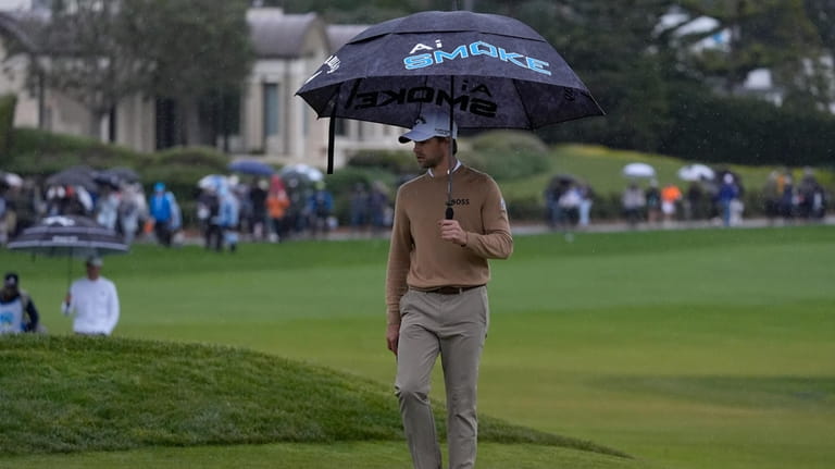 Thomas Detry carries an umbrella while approaching the 18th hole...