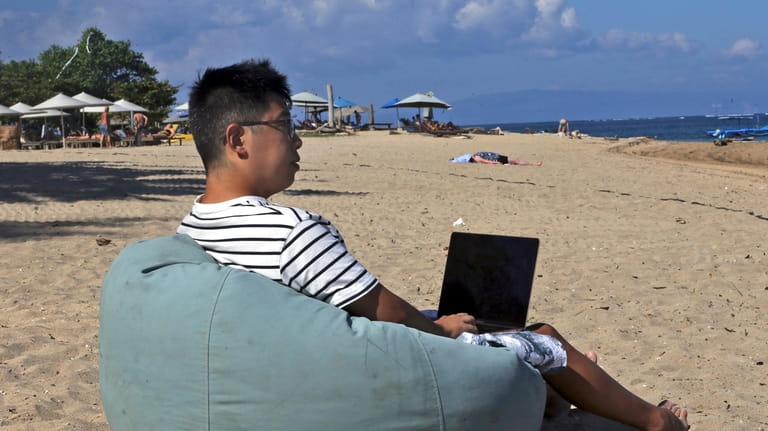 Chinese Armonio Liang sits on a beach as he works...