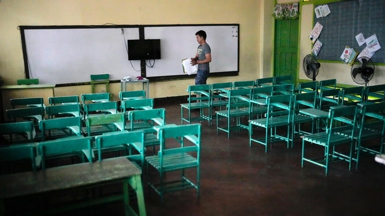 A teacher arranges papers at an empty classroom at the...