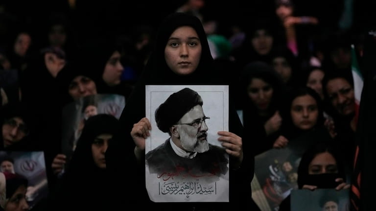 A woman holds a poster of the late Iranian President...
