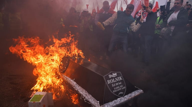 Demonstrators symbolically burn a coffin with the word "farmer" written...