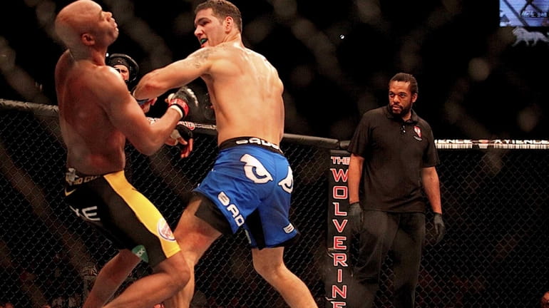 Chris Weidman knocks down Anderson Silva with a left hook...