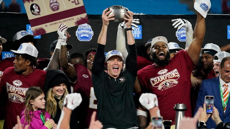 Florida State coach Mike Norvell lifts the trophy after the...