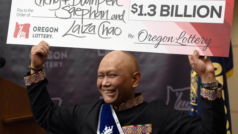Cheng "Charlie" Saephan holds a check above his head after...