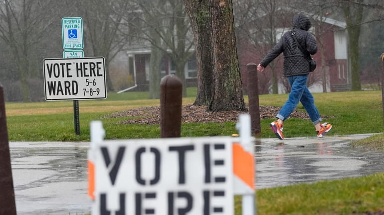 A voter braves a cold rain running to cast a...