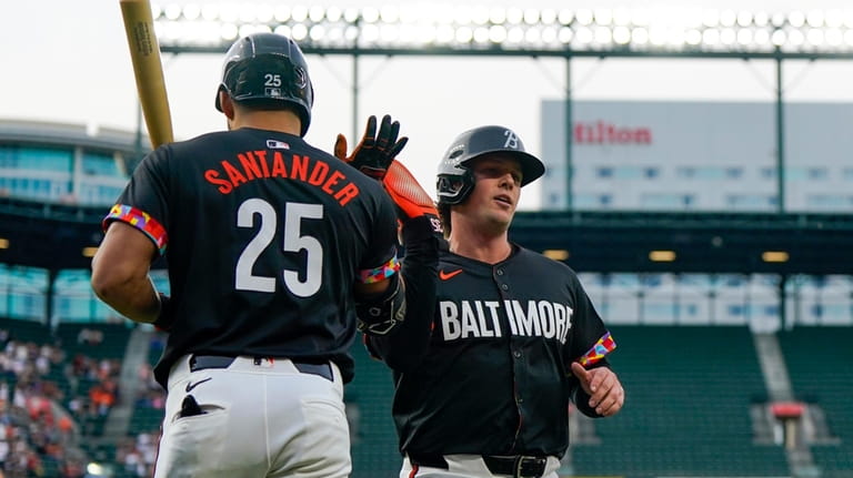 Baltimore Orioles' Adley Rutschman, right, high-fives Anthony Santander (25) after...
