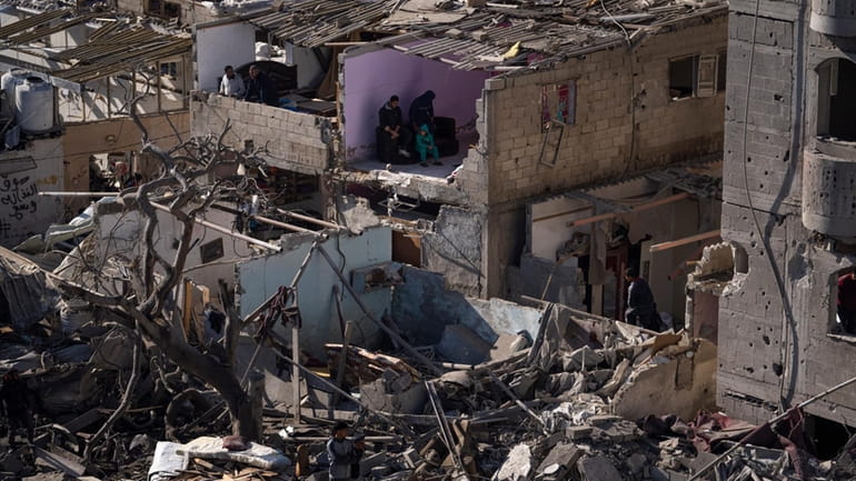 Palestinians look at the destruction after an Israeli strike on...