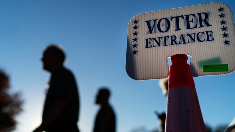 Voters pass a sign outside a polling site in Warwick,...