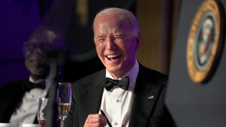 President Joe Biden laughs as host Colin Jost speaks at...