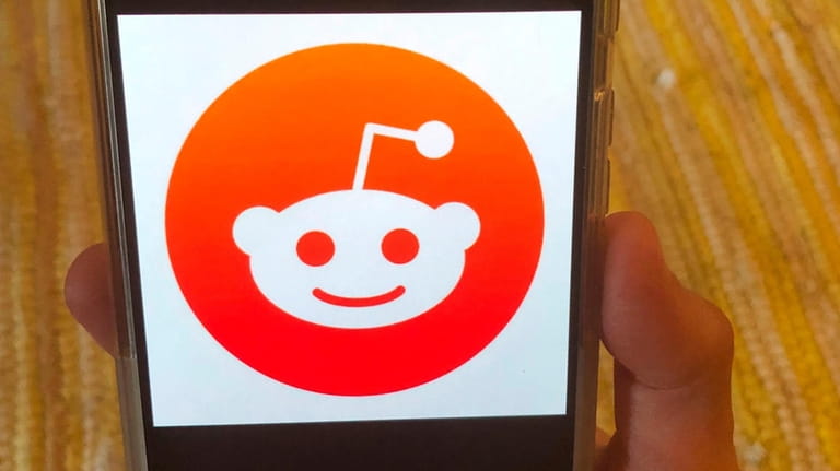 The Reddit logo is displayed on a mobile device in...