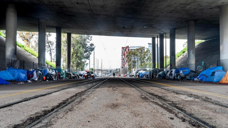 Under a freeway overpass hundreds of people live in a...