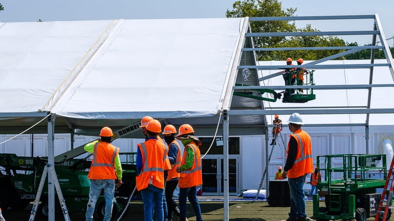 Crews put up tent dorms for migrants Sunday on Randall's Island.