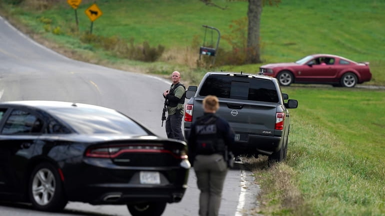 Law enforcement officers hold rifles while investigating a scene, in...