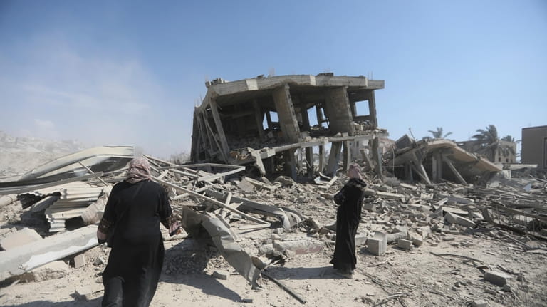 Palestinians inspect the destruction left by the Israeli air and...