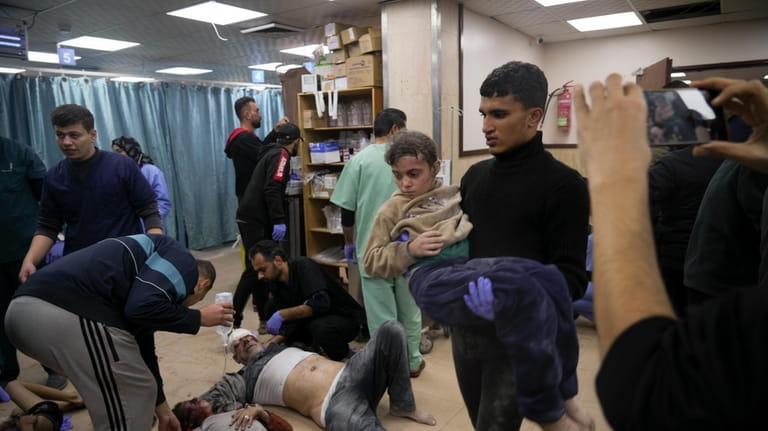 Palestinians wounded in Israeli bombardment are helped in a hospital...