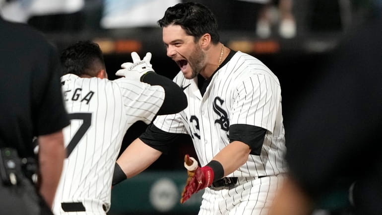 Chicago White Sox's Andrew Benintendi, right, begins to celebrate after...