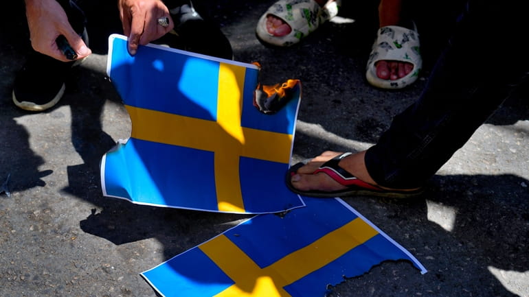 Hezbollah supporters trample representations of the Swedish flags during a...
