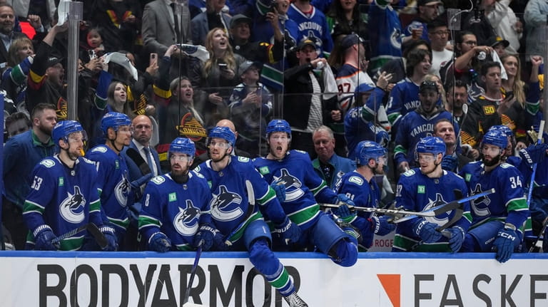 Vancouver Canucks come off the bench to celebrate after the...
