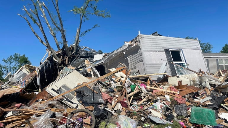 A storm damaged mobile home is surrounded by debris at...