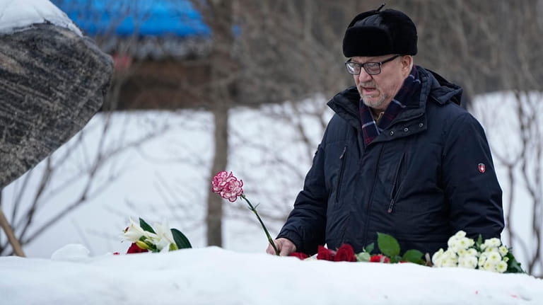 A man lays flowers to pay tribute to Alexei Navalny...