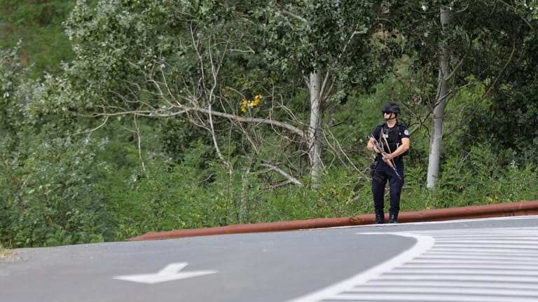 A Kosovo police officer guards the road near the village...