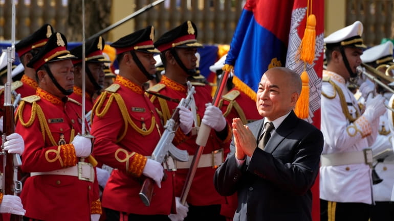 Cambodia's King Norodom Sihamoni, foreground, greets as he heads back...