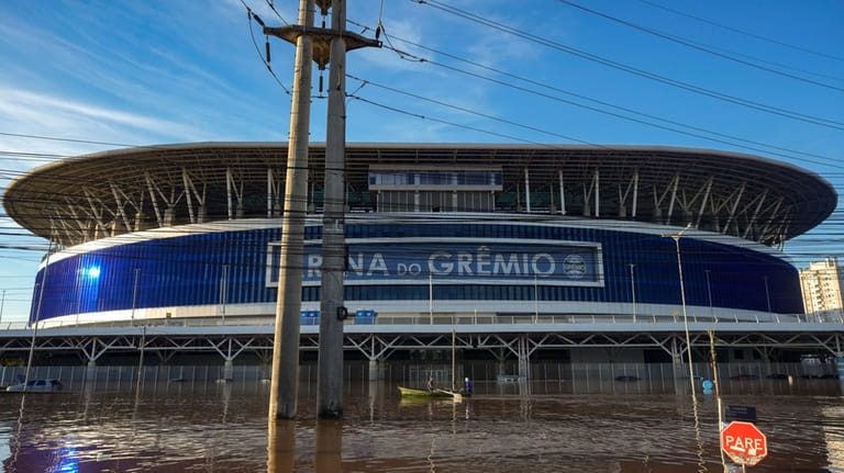 Residents row past the Gremio Arena surrounded by flood waters...