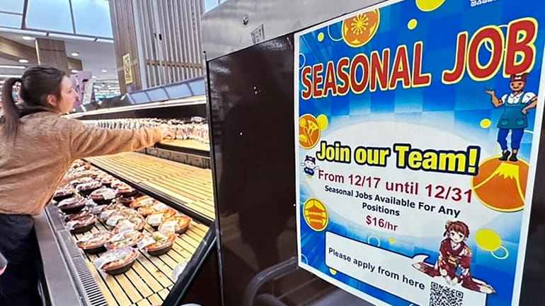 A hiring sign is displayed at a grocery store in...