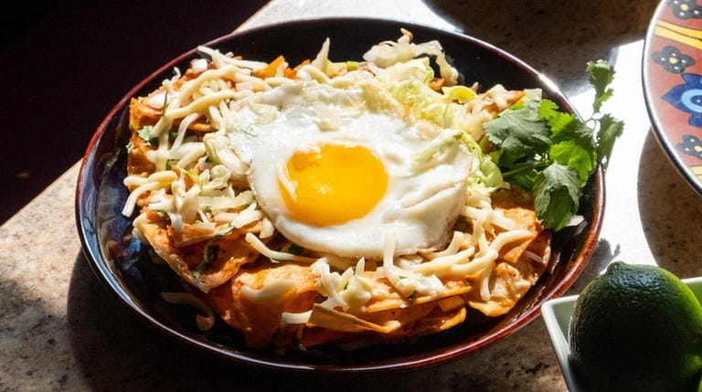 Chilaquiles, fried tortillas topped with a sunny side up egg,...