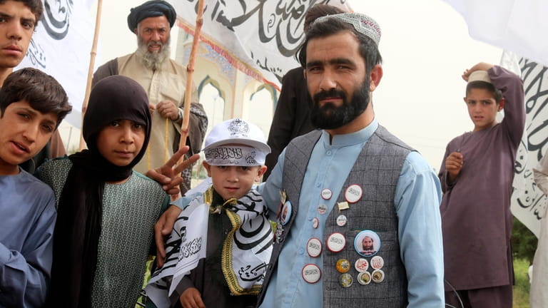 A supporter of Taliban shows off portraits of Taliban leader...