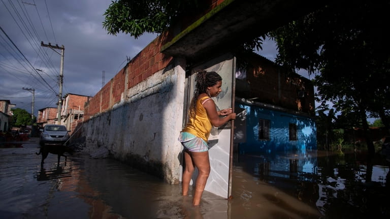 Rosimery de Jesus closes the gate at her flooded home...