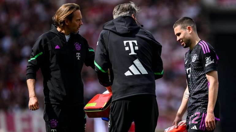 Munich's Raphael Guerreiro, right, leaves the pitch injured, during the...