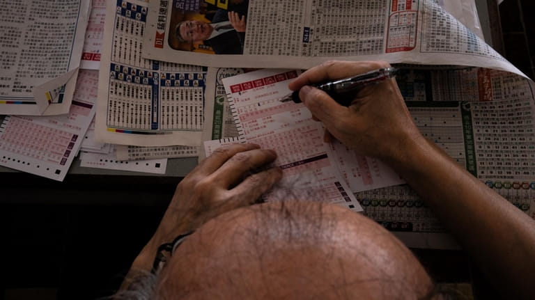 A visitor fills in betting slips at the Macao Jockey...