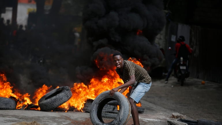 A protester adds tires to a burning barricade during a...