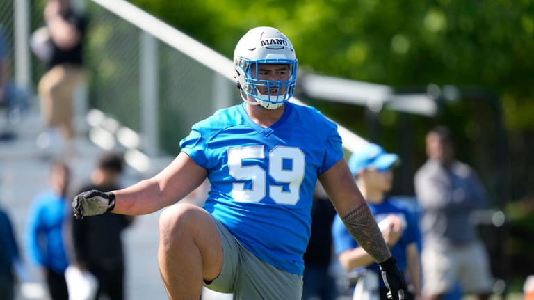 Detroit Lions offensive lineman Giovanni Manu stretches during an NFL...