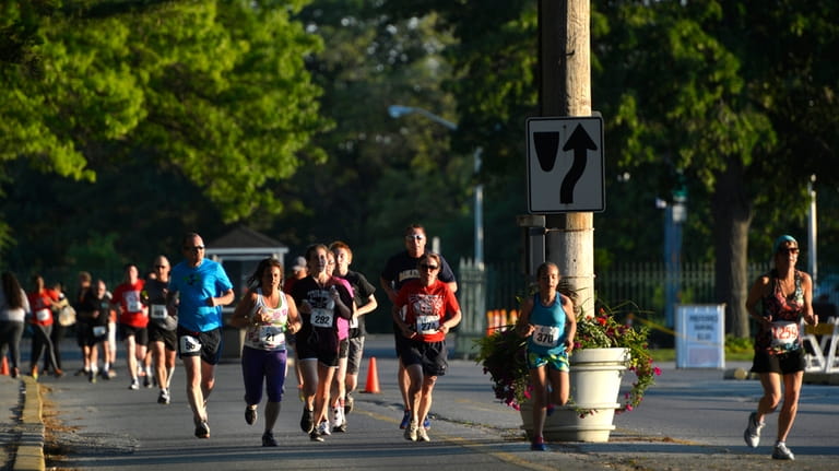 Runners from across Long Island cross the parking lot and...