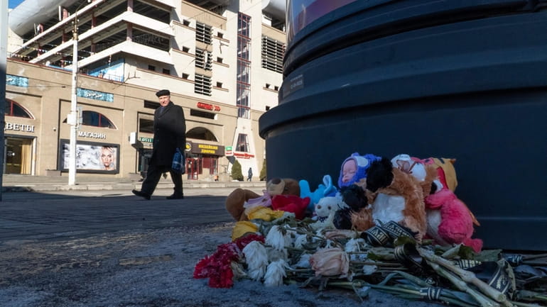 Flowers and toys lie on the ground at a makeshift...