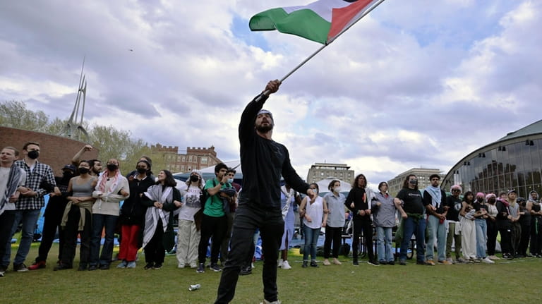 A demonstrator waves a Palestinian flag at a pro-Palestinian encampment...