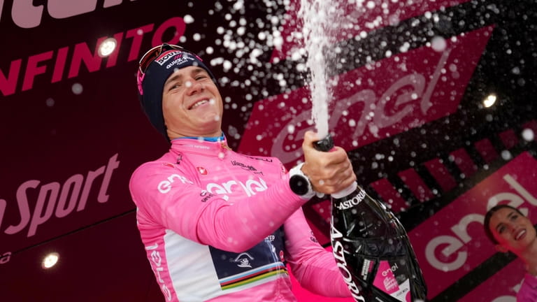 Remco Evenepoel wears the pink jersey of the race overall...