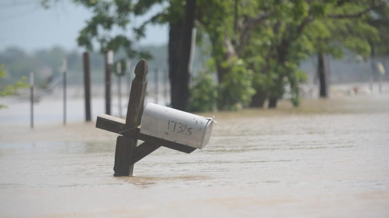 A mailbox is partially submerged on a flooded street in...