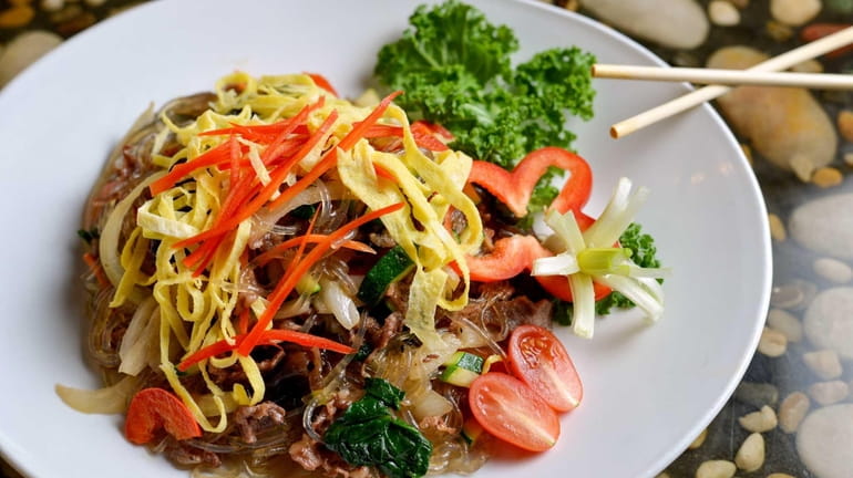 Japchae, clear sweet potato noodles, are stir-fried with assorted vegetables...