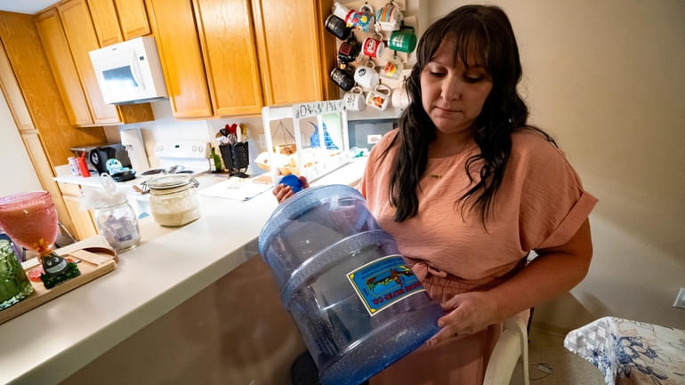 I Richelle Dietz holds an empty five-gallon water bottle at...