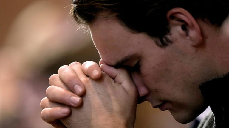 A man prays during Catholic Mass at Benedictine College Sunday,...