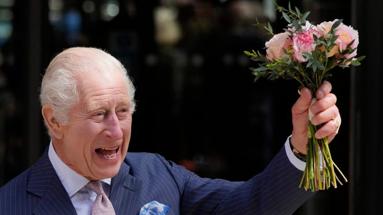 Britain's King Charles III holds up flowers he was given...