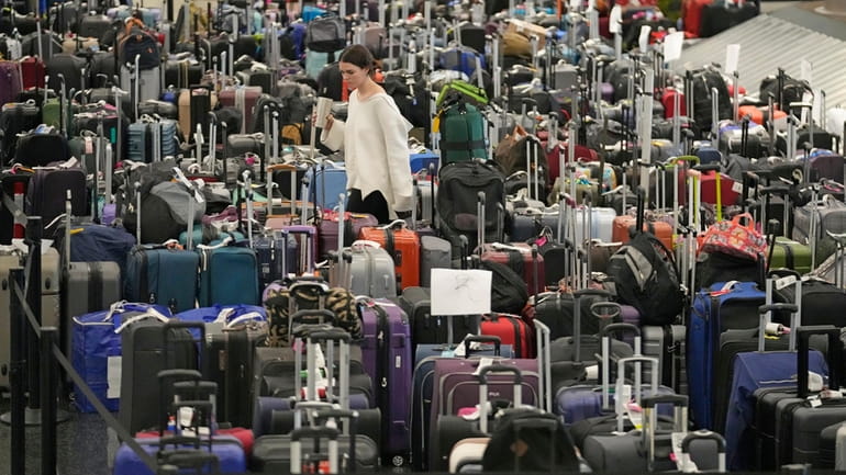 A woman walks through unclaimed bags at a Southwest baggage claim...