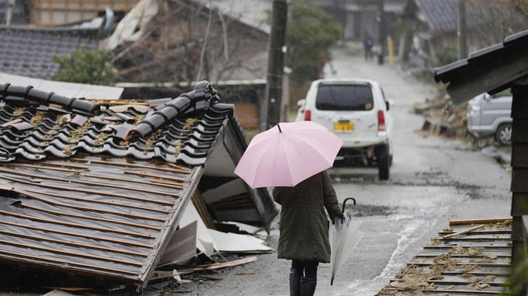 A person walks through the collapsed houses in Suzu, Ishikawa...